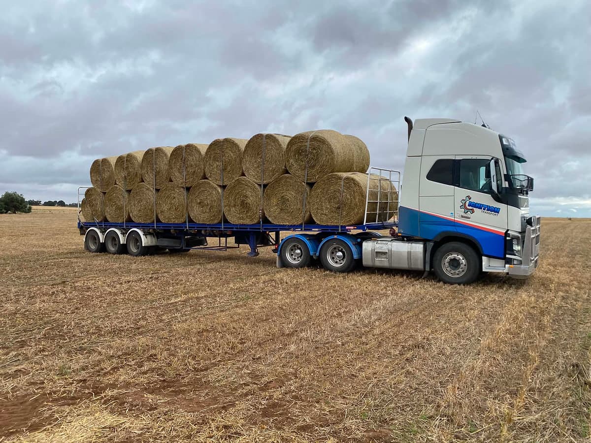 Semi loaded with round hay bales in a paddock