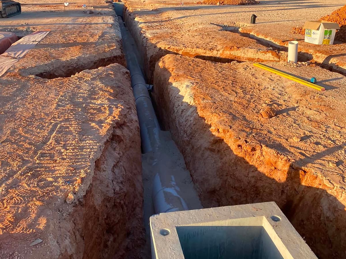 Open trench with pipe laid and a concrete pit in place