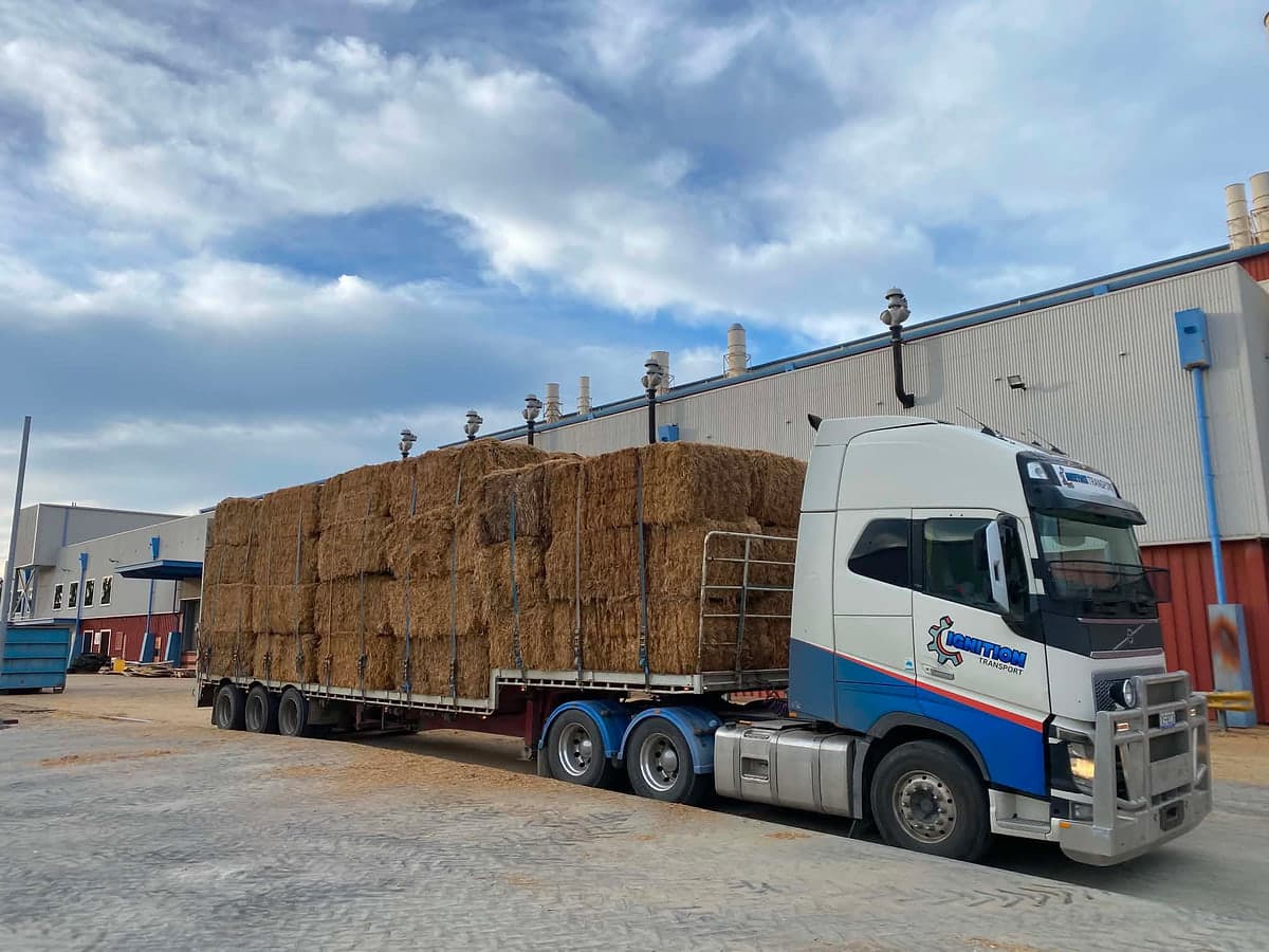 Semi loaded with hay bales outside a shed